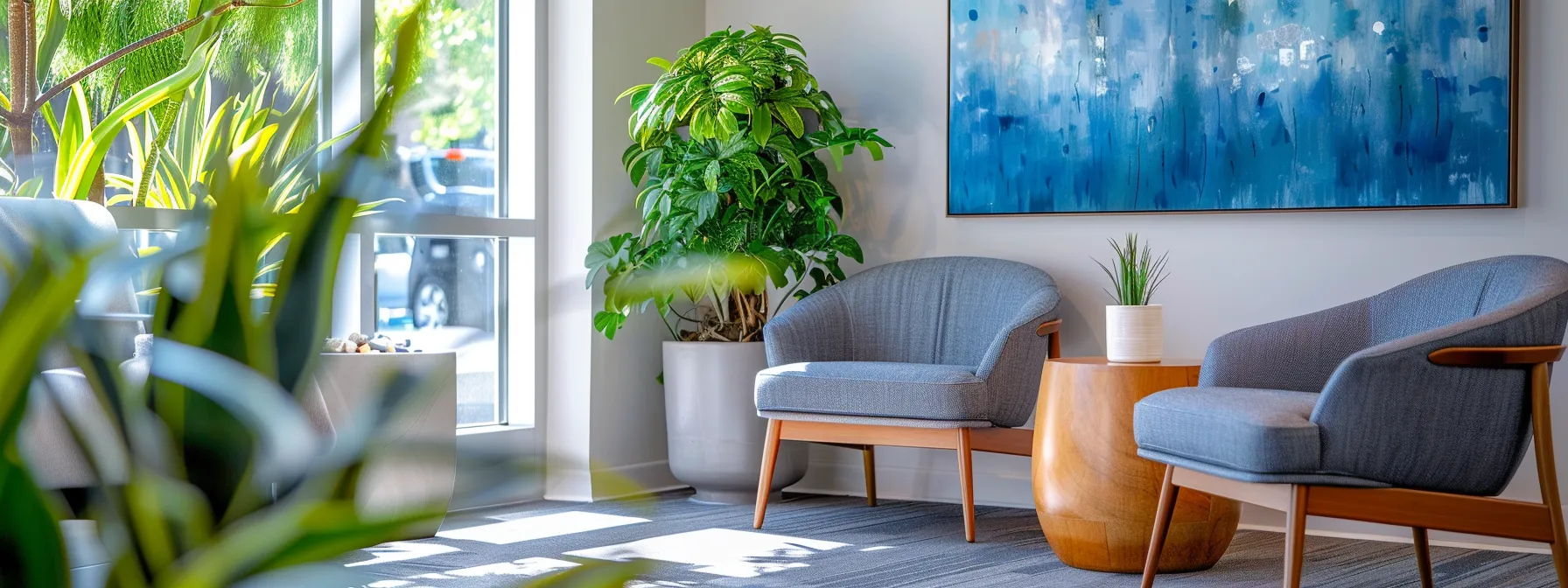 a serene and inviting therapy office interior bathed in warm natural light, featuring comfortable modern seating in calming blue and grey tones, with abstract art on the walls and peaceful indoor plants, creating an atmosphere of tranquility and safety.