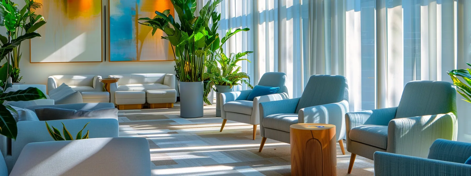 a serene therapy office featuring modern seating in soothing blue and grey tones, illuminated by gentle sunlight pouring through large windows, complemented by peaceful indoor plants and abstract art, creating an inviting atmosphere that fosters healing and recovery.