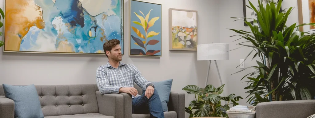 a warm and inviting therapy office interior in tennessee, featuring comfortable modern seating in soothing blue and grey tones, adorned with abstract art, serene indoor plants, and soft, ambient lighting that conveys a sense of safety and tranquility.